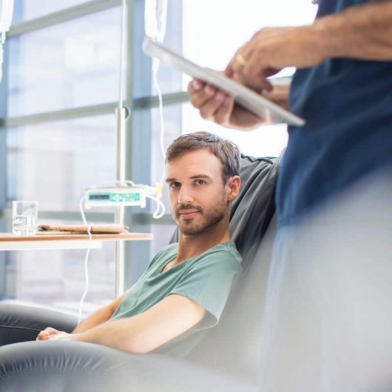 Male patient sitting in an infusion chair, looking at the camera.