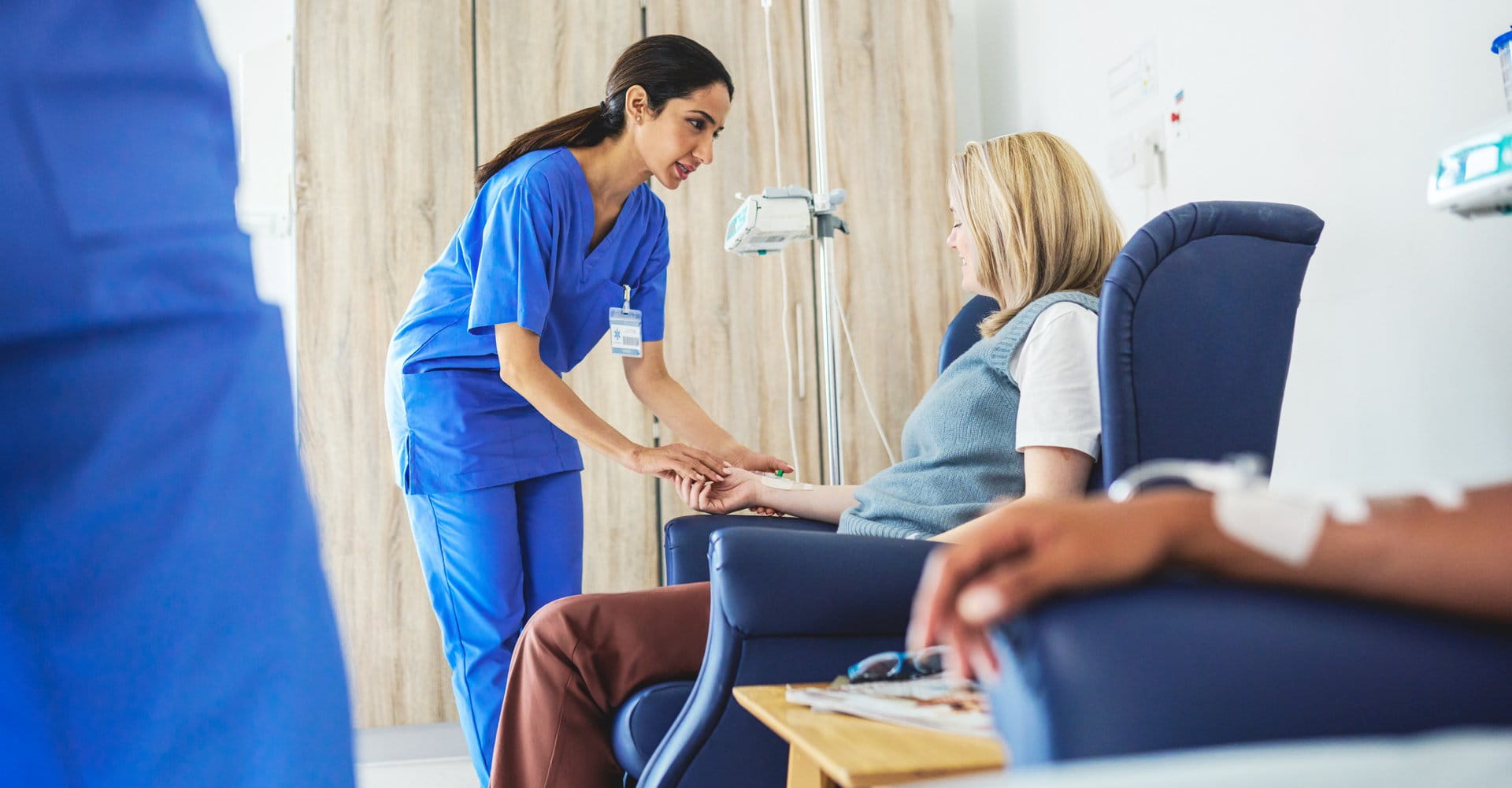 A nurse checking in on a patient in an infusion chair.